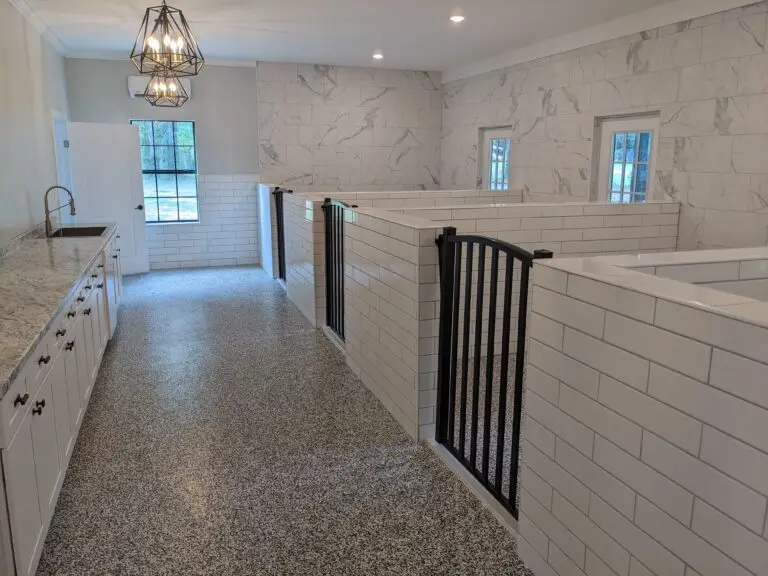 Interior view of The Noble Nose Canine Boarding's luxurious dog run kennel area with subway-tiled walls, and sleek black gates in Greenwood, LA