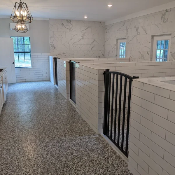 Interior view of The Noble Nose Canine Boarding's luxurious dog run kennel area with subway-tiled walls, and sleek black gates in Greenwood, LA